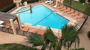 A rectangular pool with a surrounding deck, lounge chairs, and palm trees. - Beachfront...South Corner 3 Bedroom With Spectacular Views (South Padre Island)