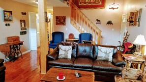 A cozy living room with a brown leather sofa, a wooden coffee table, and a staircase leading to another level. - Close to all attractions (Sevierville)