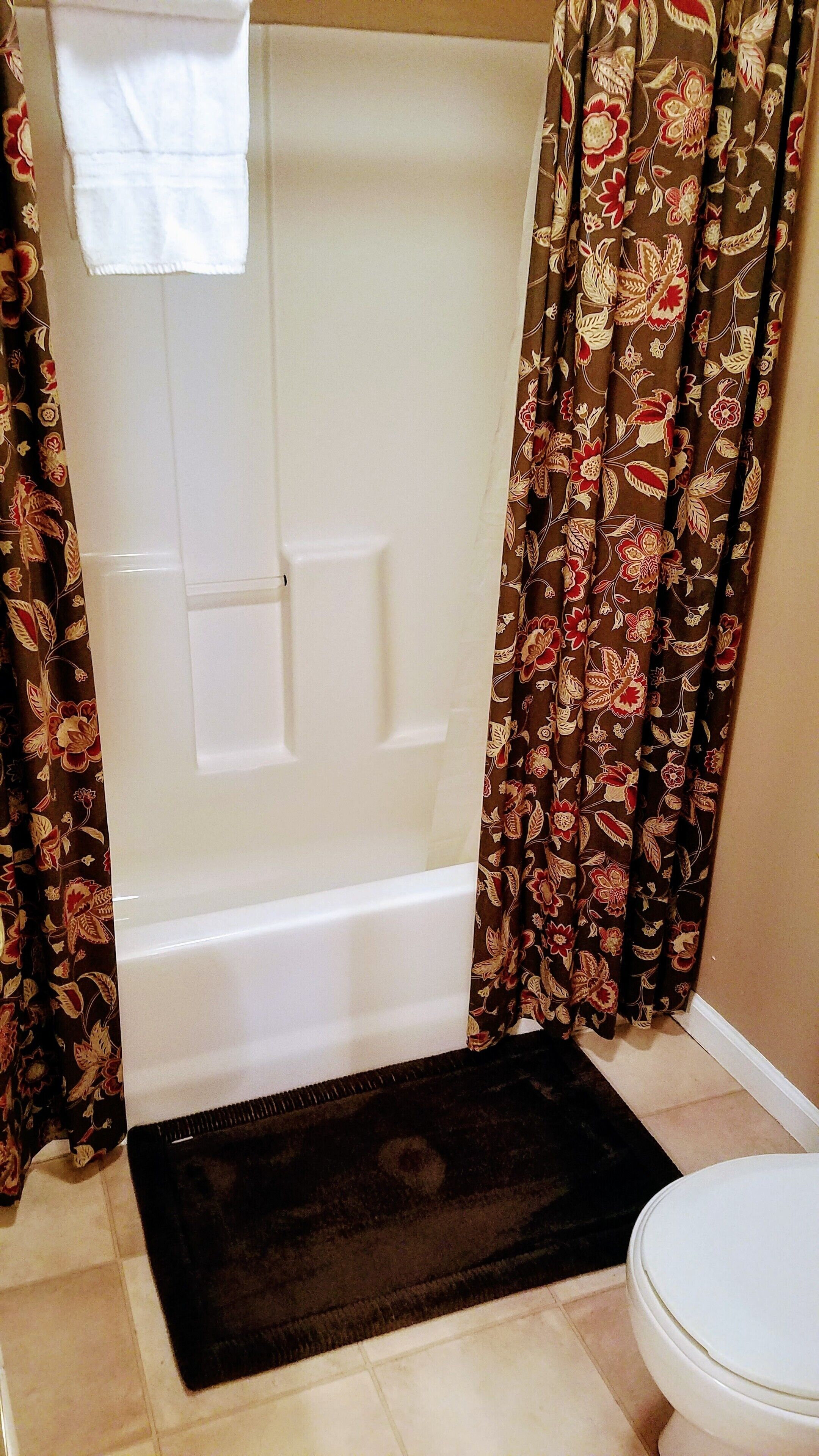 A bathroom with a bathtub, a toilet, and a shower curtain with a floral pattern.