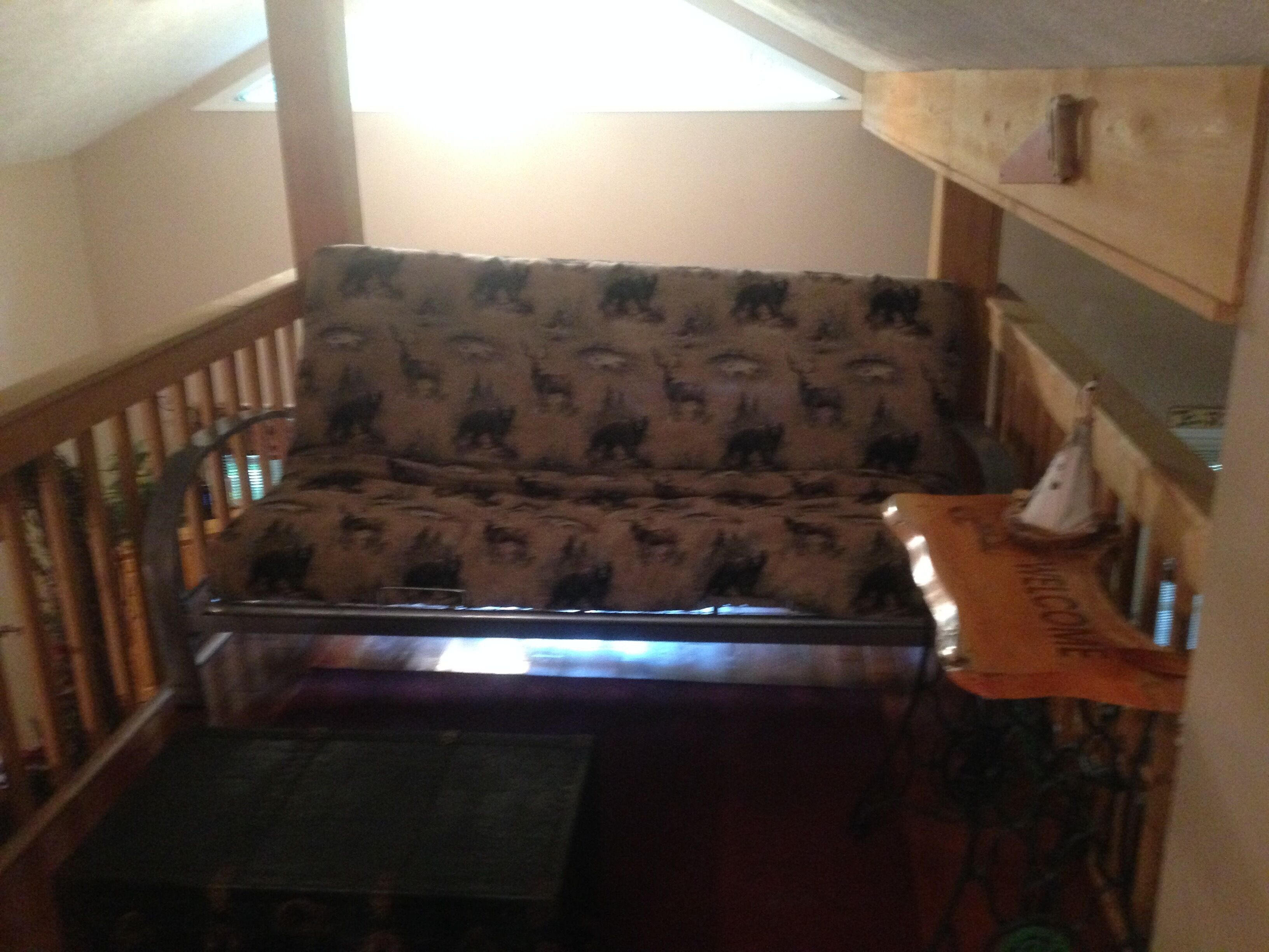 A room with a patterned sofa, a small table, and a wooden railing.