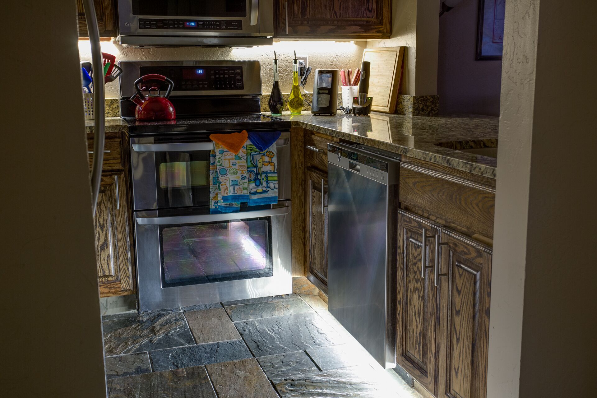 A kitchen with a microwave, oven, and dishwasher. There are various kitchen utensils and appliances on the counter.