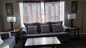 A living room with a grey sofa, patterned cushions, a coffee table, and two side tables with lamps. - Private Upscale Condo in Myrtle w/ Ocean View Across from Boardwalk w/ Huge Deck (Myrtle Beach)