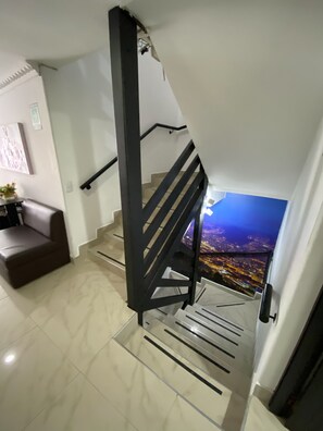 A modern staircase with a black metal railing, leading to a balcony with a city view at night. - Lleras Premium Hotel (Medellín)