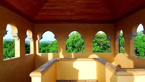 Un balcón con techo y arcos de madera, con vistas a zonas verdes.