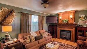 Una sala de estar acogedora con un sofá, una mesa de centro, una chimenea y un televisor.