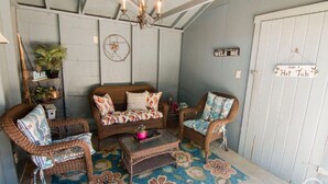 Una habitación acogedora con muebles de mimbre, un tapiz floral y un candelabro.