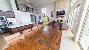 Une cuisine spacieuse dotée d’un grand îlot central, d’une table à manger en bois et d’un escalier menant à un niveau supérieur.