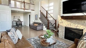 Un salon spacieux avec un canapé en cuir marron, une cheminée et un mur décoratif en pierre.