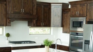 Une cuisine moderne avec des meubles en bois foncé, un plan de travail blanc, des appareils électroménagers en acier inoxydable et des tabourets de bar.