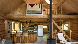 L’intérieur d’une cabane en rondins comprend une cuisine, un coin repas et un salon.