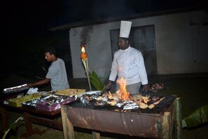A chef grilling food outdoors at night. - Mihini hotel (Habarana)