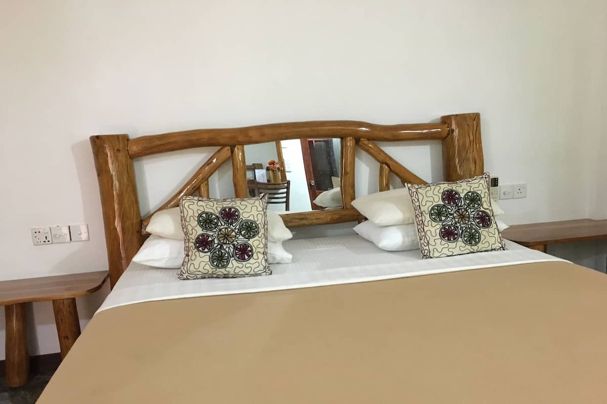 A bed with a wooden headboard, two decorative pillows, and a bedside table.