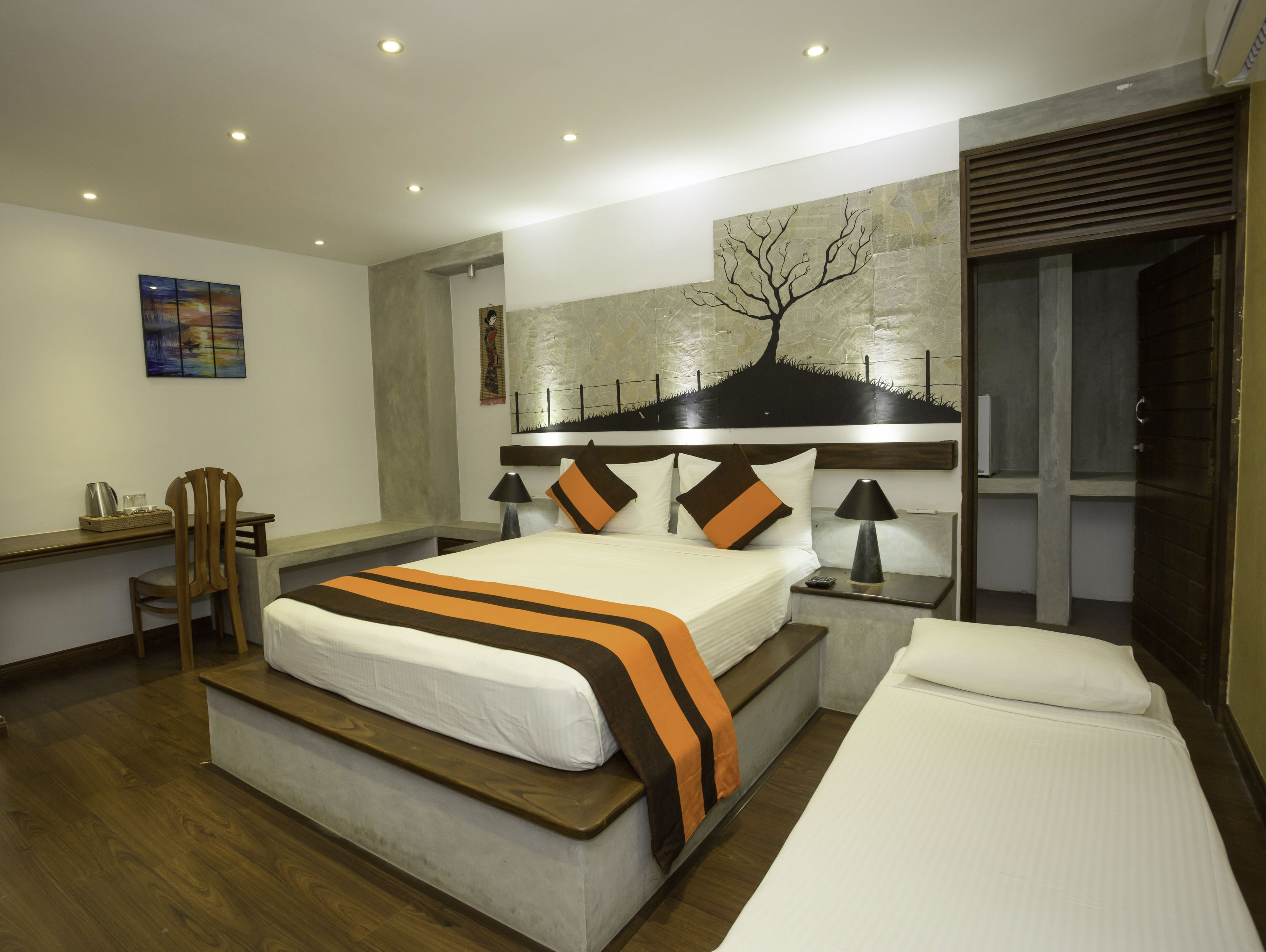 A modern hotel room with a large bed, bedside tables, a desk, and a chair.