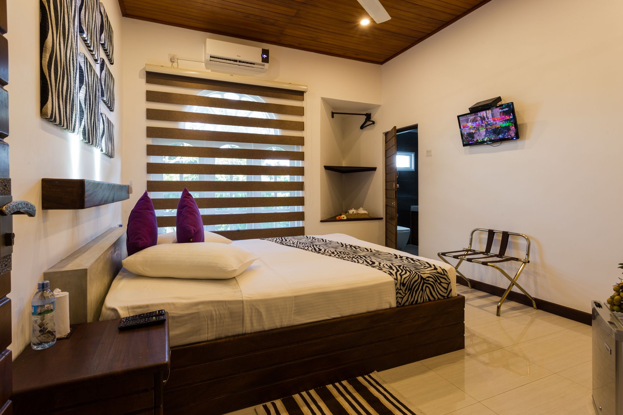 A modern bedroom with a bed, a TV, a water bottle, and a chair.