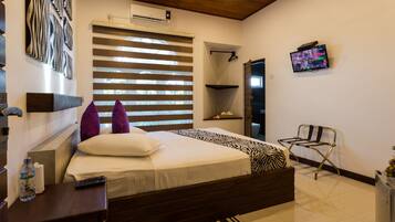 A modern bedroom with a bed, a TV, a water bottle, and a chair.