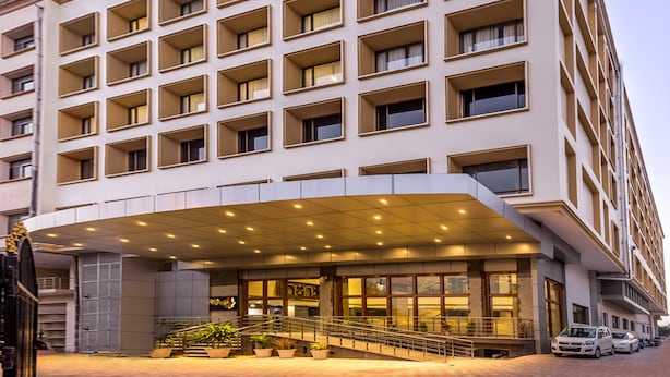 A multi-story hotel with a modern facade, large windows, and a covered entrance area. - Hotel Saptagiri (Hyderabad)