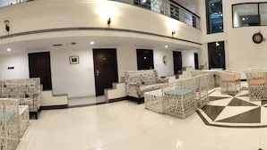 A spacious lobby with multiple seating areas, a checkered floor, and a second-floor balcony. - Hotel Saptagiri (Hyderabad)