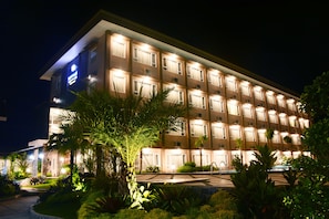 A multi-story hotel with a well-lit facade, a swimming pool, and landscaped gardens. - Mexolie Hotel (Kebumen)