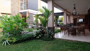 A courtyard with a dining area, stone walls, and tropical plants. - Mexolie Hotel (Kebumen)