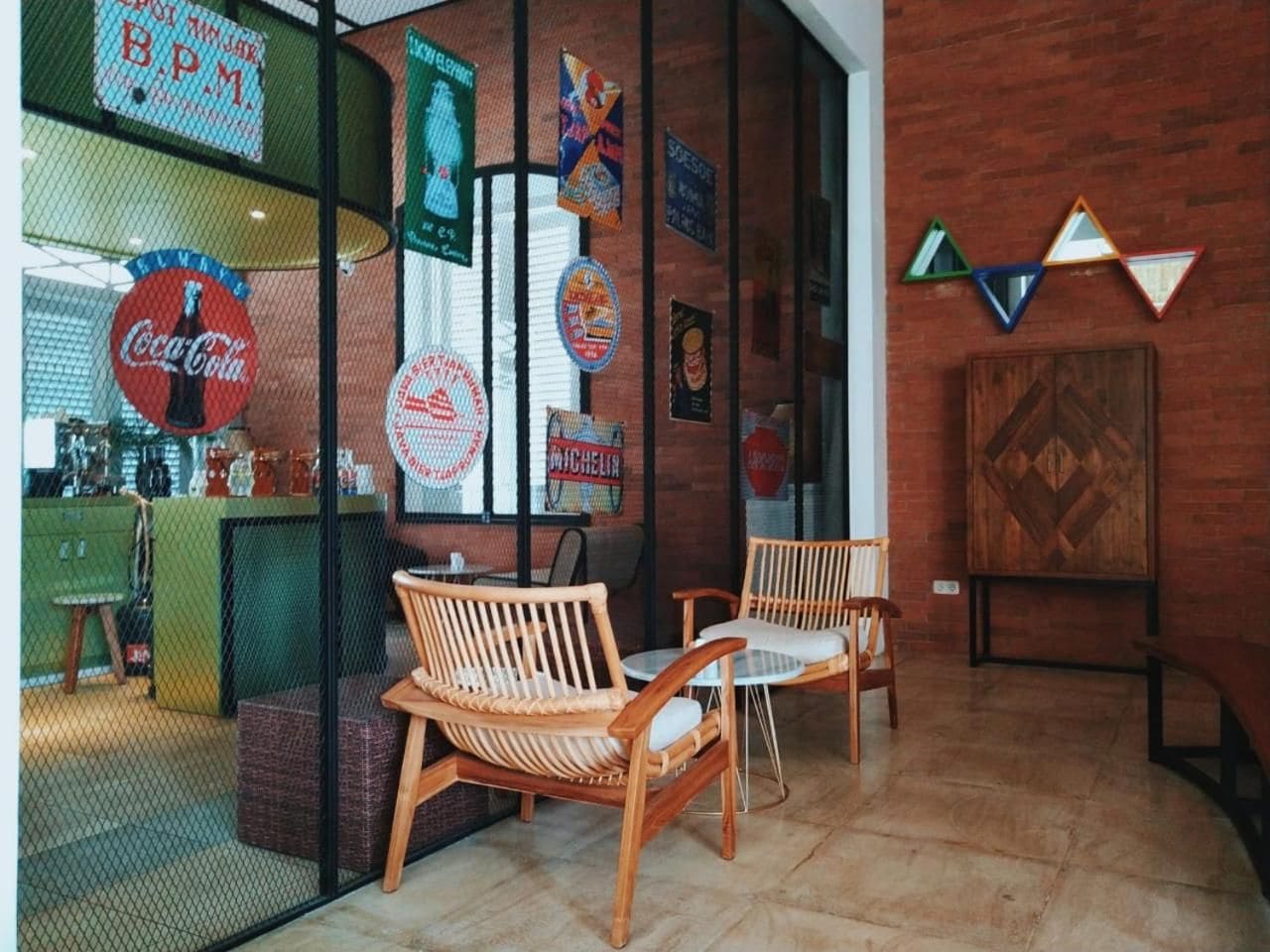 Interior de café com cadeiras de madeira, balcão verde e diversos cartazes nas paredes.