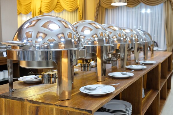 A buffet setup with multiple food service stations, each with a dome-shaped cover and a spoon on a plate. - Mexolie Hotel (Kebumen)