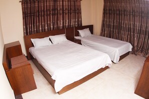 A double bed with a wooden headboard, two bedside tables, and a curtain with a pattern.