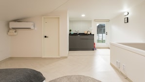 Un apartamento moderno con kitchenette, una puerta que da a un balcón y un equipo de aire acondicionado visible.