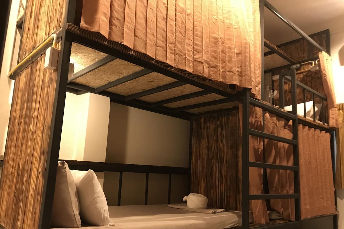 A bunk bed with a wooden headboard, a mattress, pillows, and a blanket.
