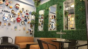 A cozy seating area with a sofa and chairs, a small table, and a wall decorated with plush toys and greenery.