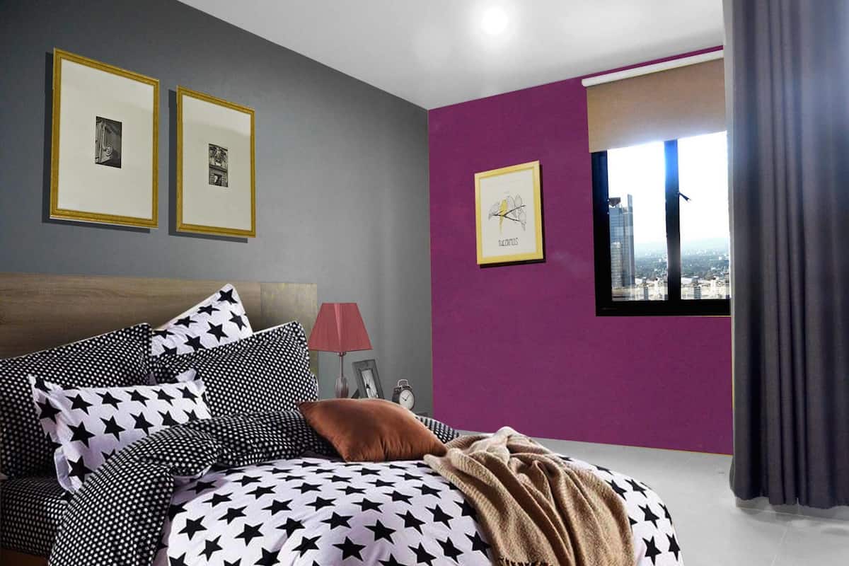 A bedroom with a bed, pillows, a lamp, and framed pictures on the wall.