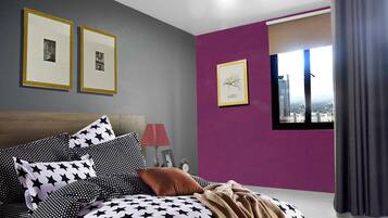 A bedroom with a bed, pillows, a lamp, and framed pictures on the wall.