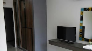 A modern hotel room with a flat-screen TV, a large mirror with geometric patterns, and a wardrobe with sliding doors. - At Yaya (Bangkok)