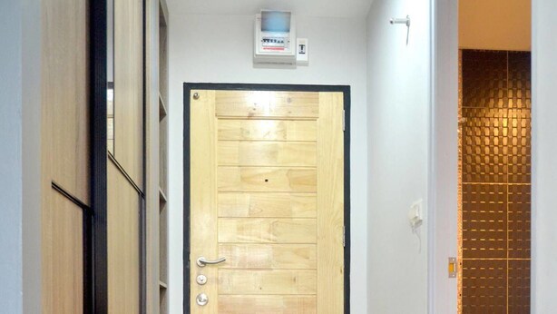 A hallway with a wooden door, a tiled floor, and a bathroom visible to the right. - At Yaya (Bangkok)