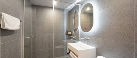A modern bathroom with a glass-enclosed shower, a white sink, and a large mirror.