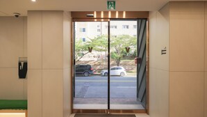 A hotel entrance with a glass door, a green mat at the entrance, and a visible parking area outside. - VIP Hotel Mokpo (Mokpo)