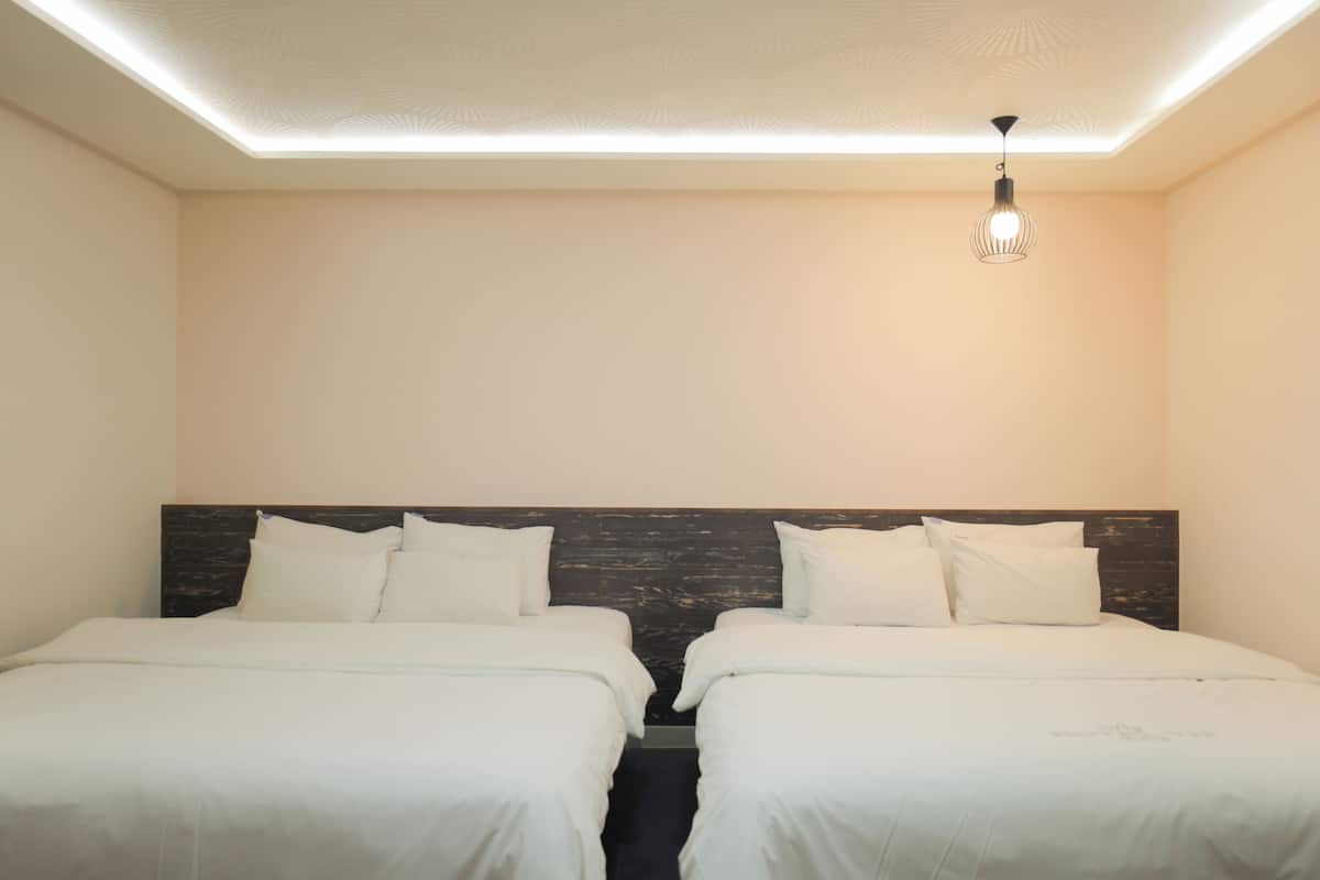 Una habitación de hotel con dos camas, un cabecero de madera y una lámpara en el techo.