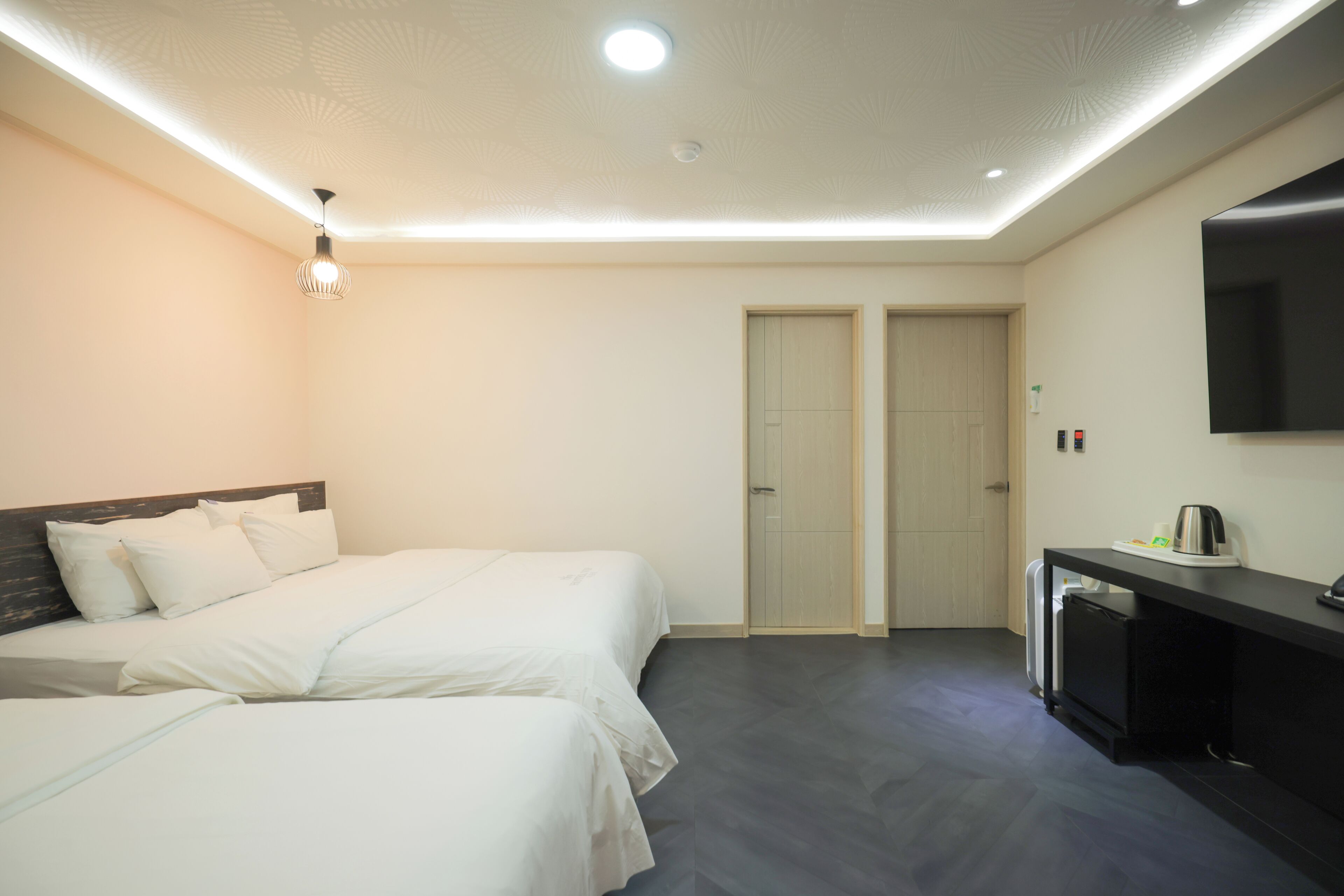 Een hotelkamer met twee bedden, een bureau, een televisie en een minibar.