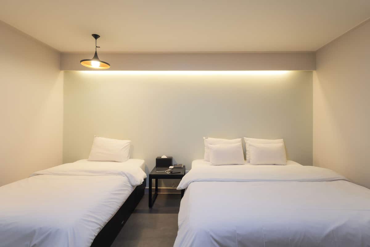 Una habitación de hotel con dos camas individuales, una mesita de noche y una lámpara en el techo.