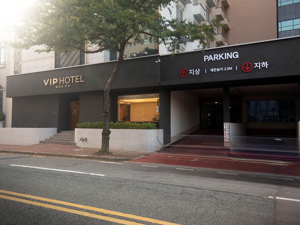 A hotel entrance with a parking sign and a tree in front.