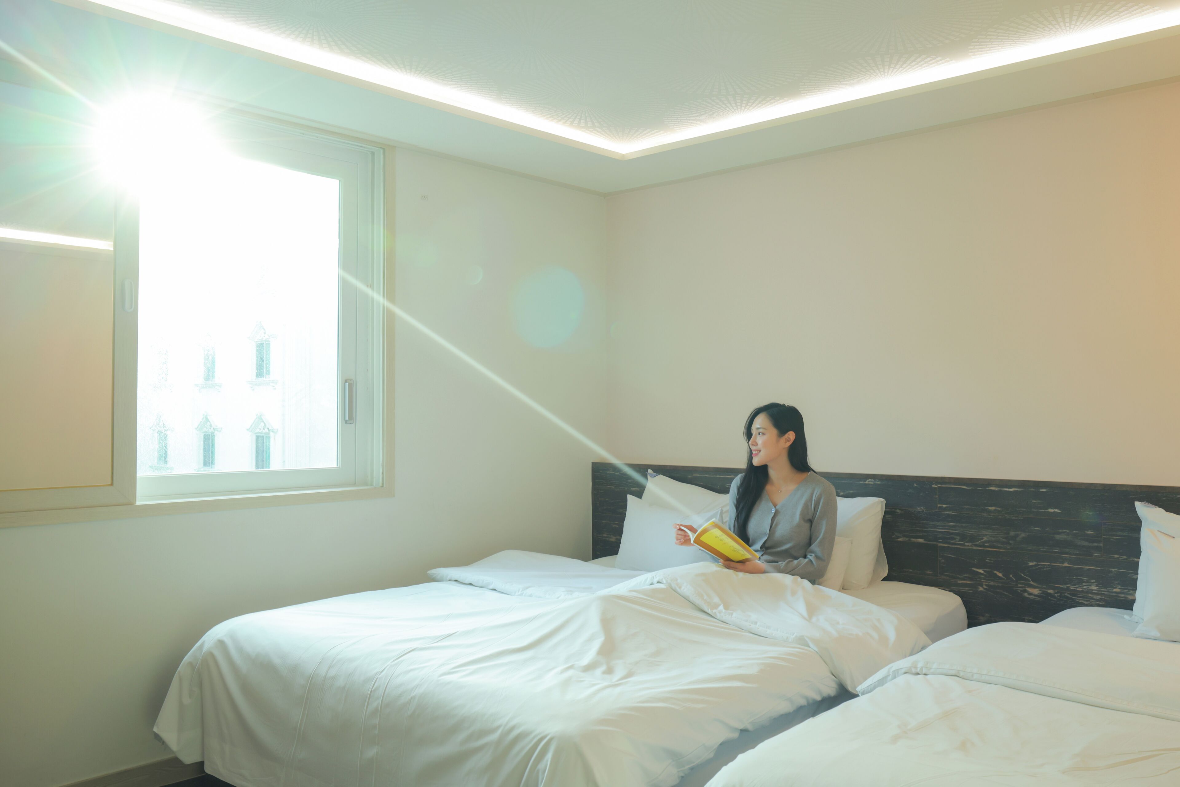 A hotel room with a bed, a window, and a reading light.