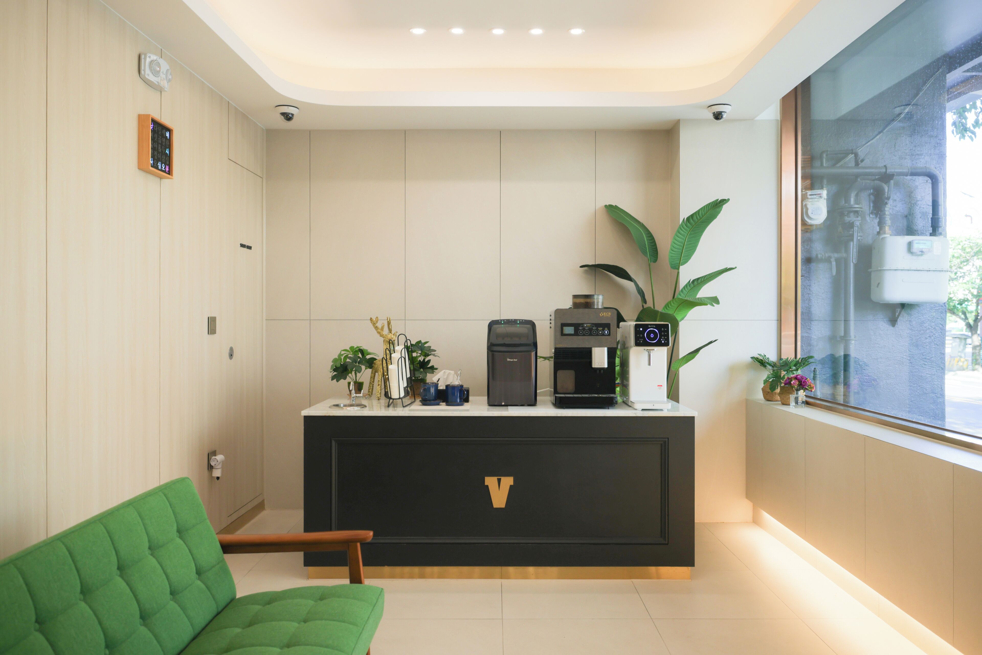 A reception area with a black counter, a green chair, and potted plants.