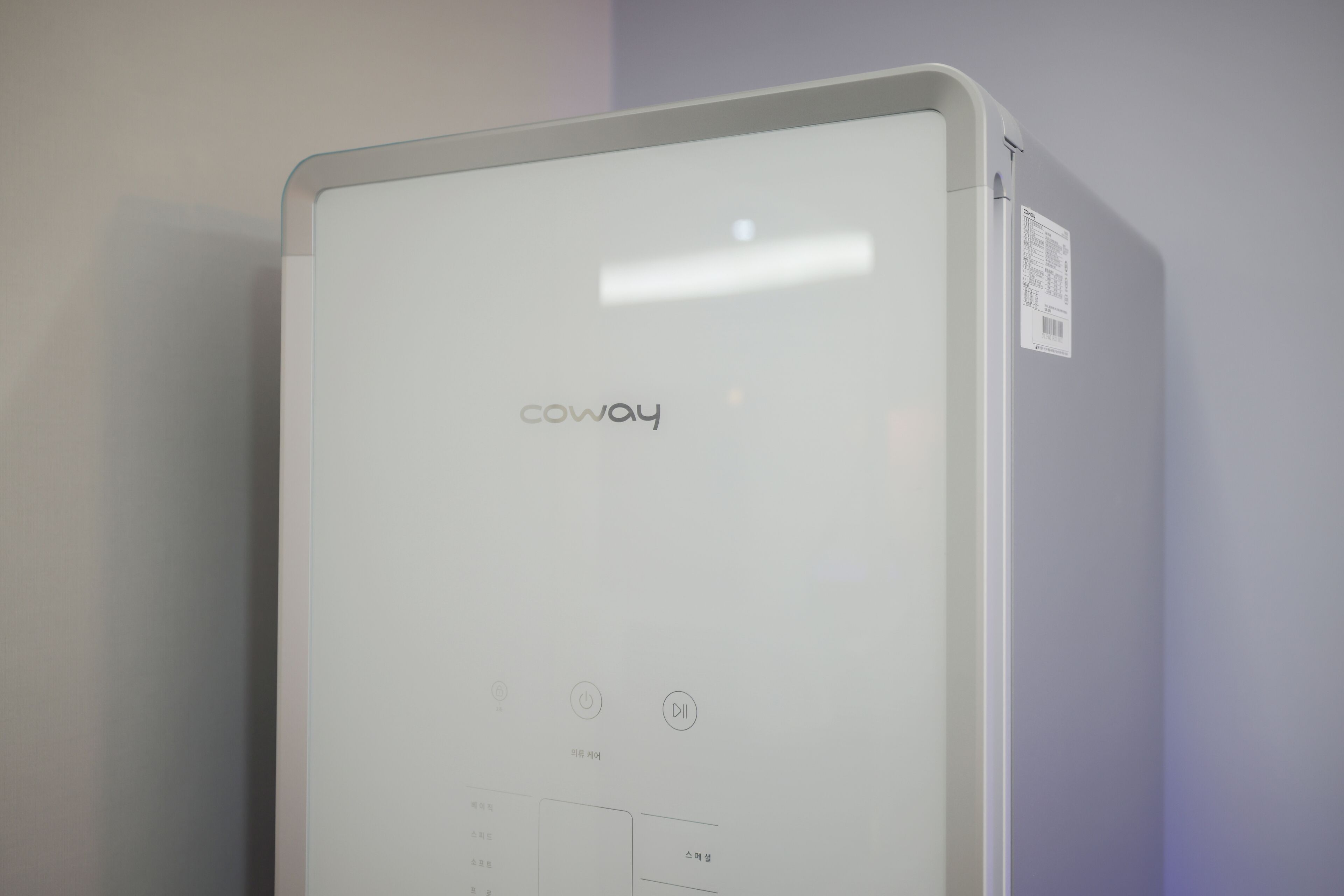 A white Coway air purifier with a control panel and a barcode sticker on the side.