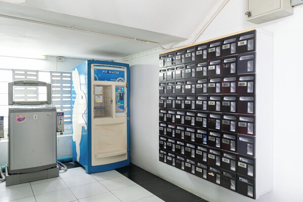 A hallway with a blue water dispenser labeled 'PIT WATER' and a wall of numbered mailboxes. - Ruan Plaisoi Apartment by Zuzu (Bangkok)