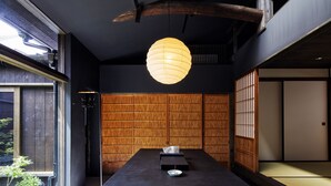 A traditional Japanese room with tatami flooring, a low table with a bowl, and a hanging paper lantern.