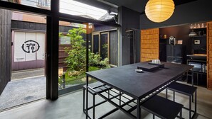 A modern interior with a large dining table, benches, and a hanging light fixture.