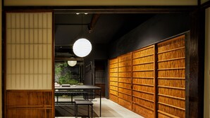 A traditional Japanese room with tatami flooring, a low table with benches, and a large wooden bookshelf.