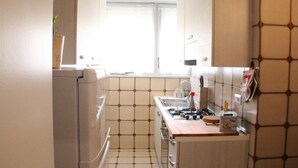 Een compacte keuken met een gasfornuis, een spoelbak en een raam dat voor daglicht zorgt.