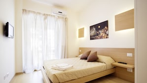 Een moderne slaapkamer met een houten bed, een nachtkastje, een wandtelevisie en een schilderij.