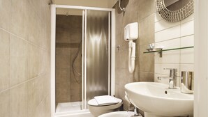 Een moderne badkamer met een ruime douche, toilet en wastafel.