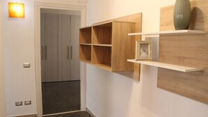 Een gang met een houten kast, een deur met lichtschakelaar en een klein fotokader op de plank.